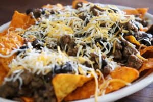 Topping the beef and beans with more shredded Mexican cheese