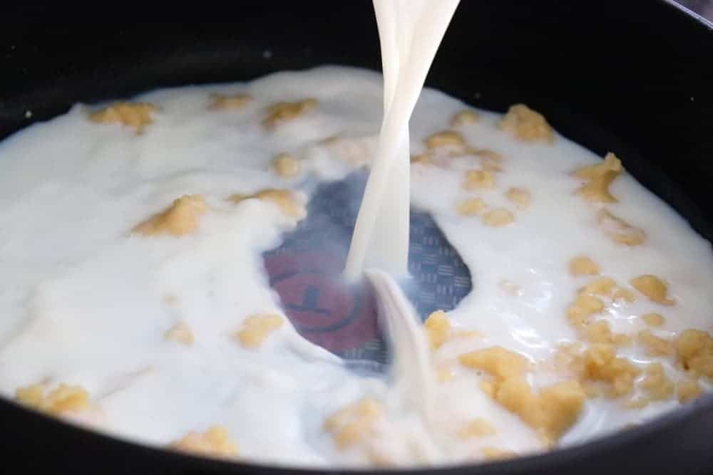 Adding milk to flour mixture to create a sauce