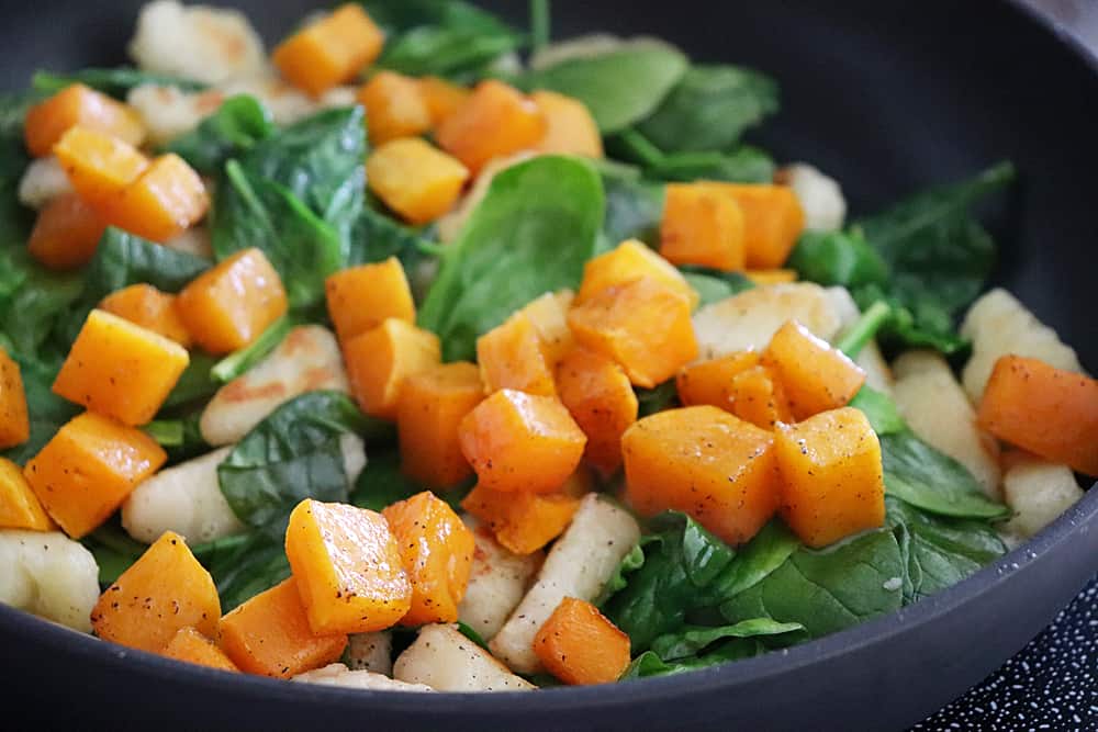 Adding roasted butternut squash to the spinach and gnocchi