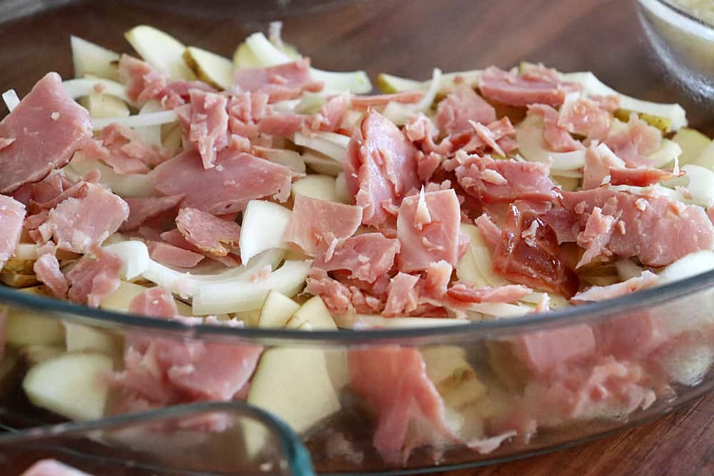 layering sliced ham and potatoes