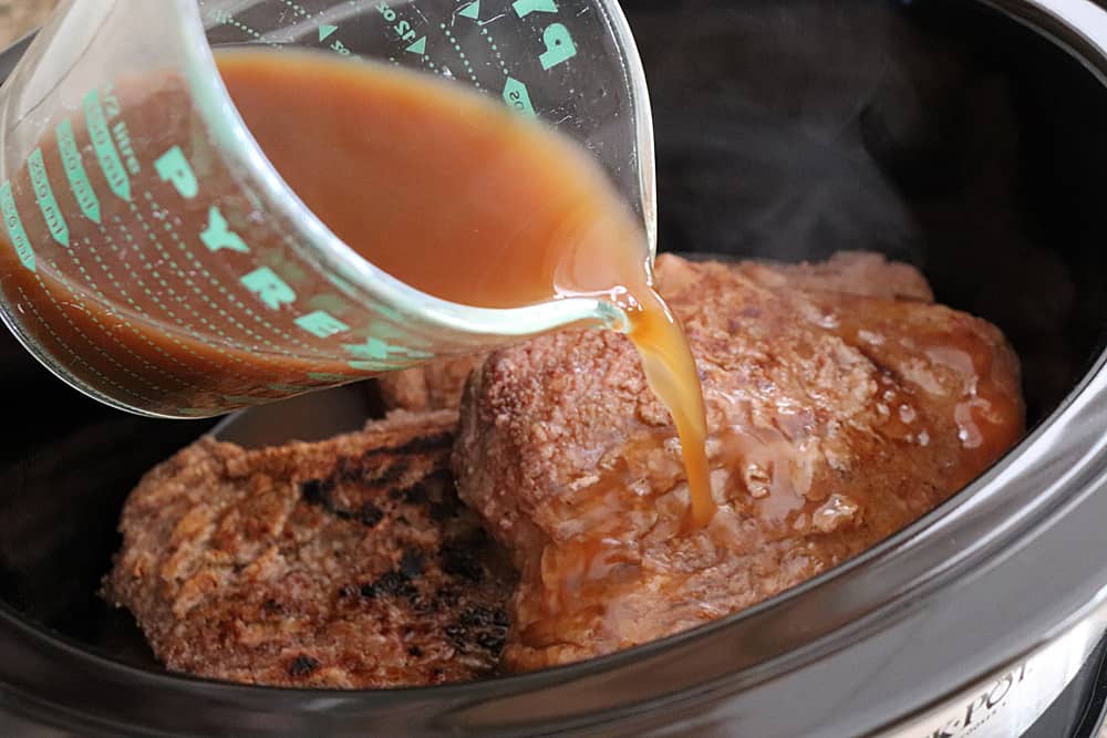 Adding broth to slow cooker for Slow Cooker Swiss Steak