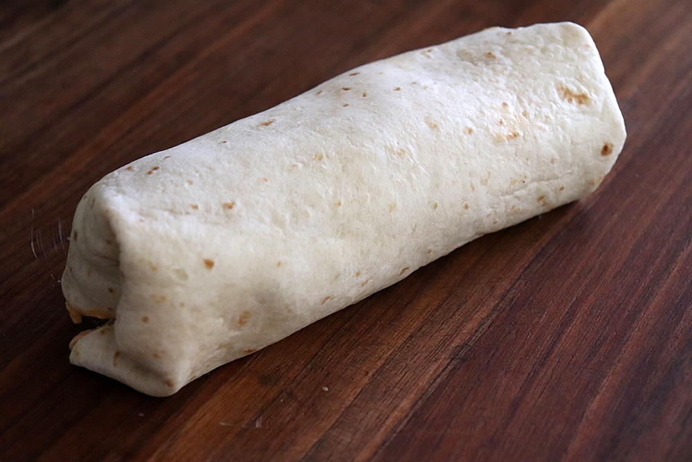 STEP 8 Fold in the sides of the tortilla, tuck in the filling and roll tightly ending with the seam side down